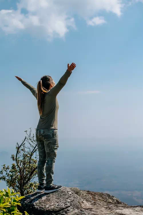 Standing on a Cliff Edge with Arms Raised Standing on a Cliff Edge with Arms Raised